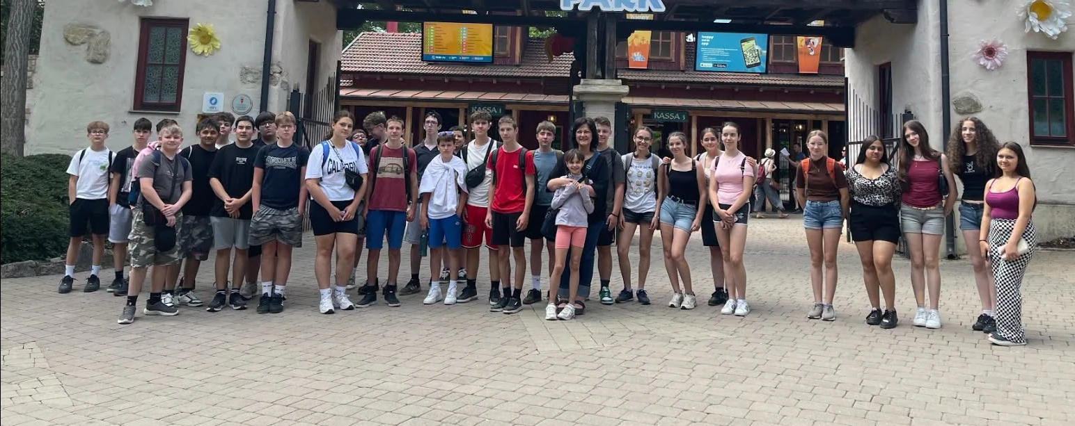 Felsős diákok osztálykiránduláson, egy vidámpark bejárata előtt